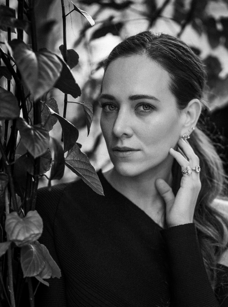 Soft editorial portrait among foliage with a direct gaze
