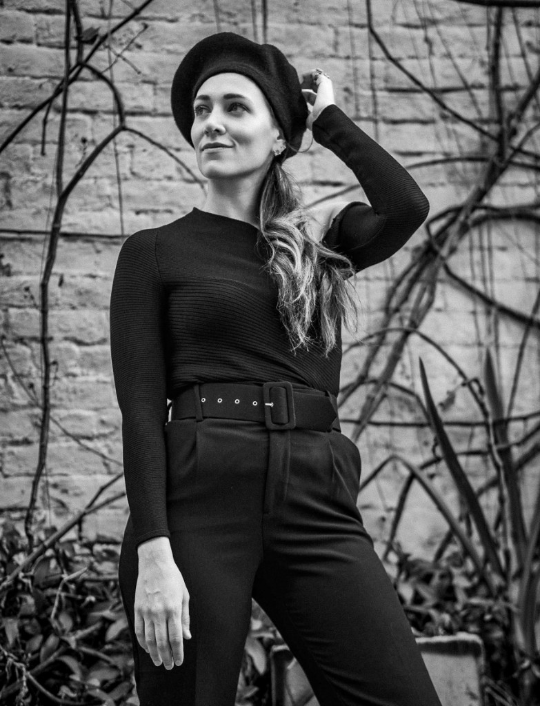 Full-length editorial portrait against an ivy-covered brick wall