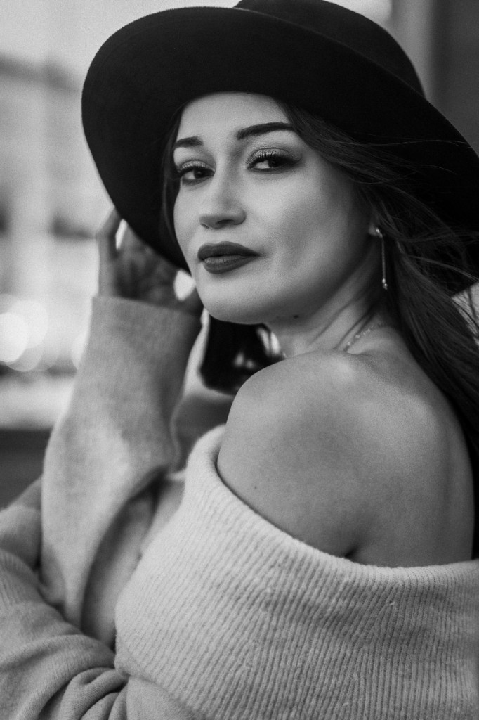 Editorial portrait in a wide-brim hat with soft urban bokeh